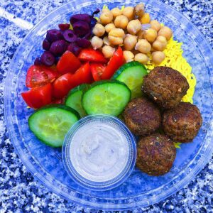 Falafel Bowl Served with turmeric rice, black olives, cucumbers, tomatoes, chick peas, and a side of tahini sauce