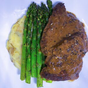 Peppercorn Steak with mashed potatoes, and a side of asparagus