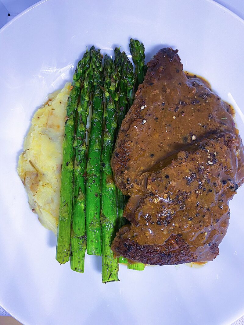 Peppercorn Steak with mashed potatoes, and a side of asparagus