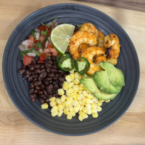 Cajun shrimp served with turmeric rice, cherry tomatoes, beans, corn, and a side of guacamole