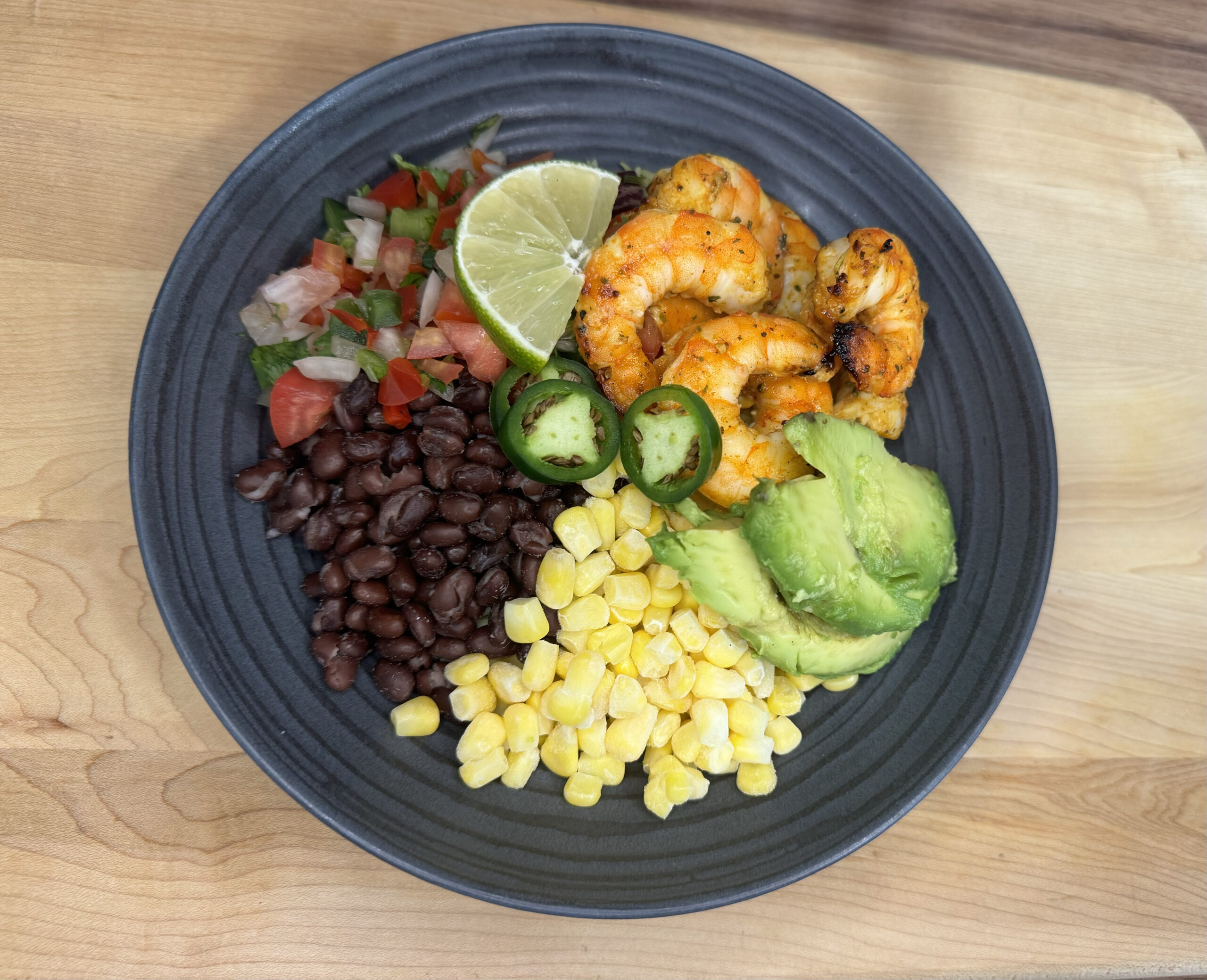 Cajun shrimp served with turmeric rice, cherry tomatoes, beans, corn, and a side of guacamole