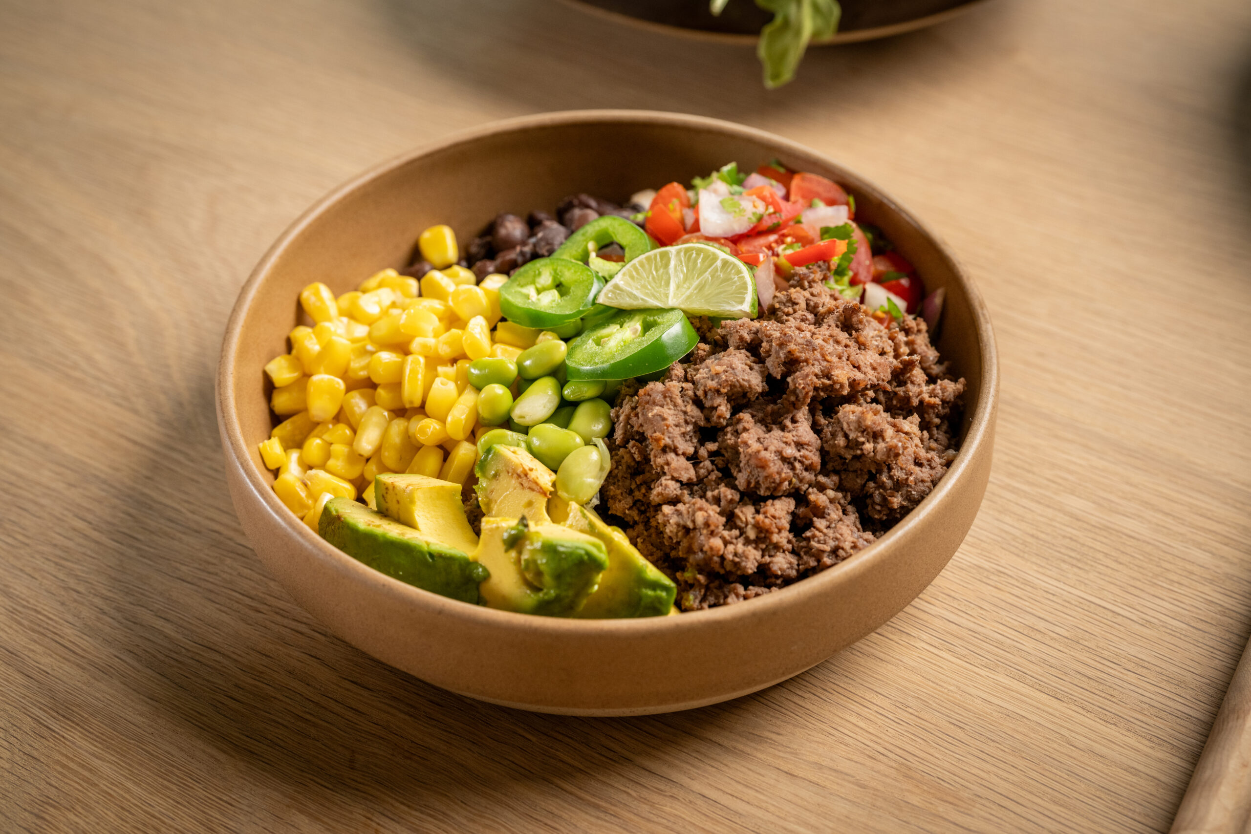 Ground beef served with basmati rice, edamame, black beans, corn, tomatoes, and a side of guacamole.