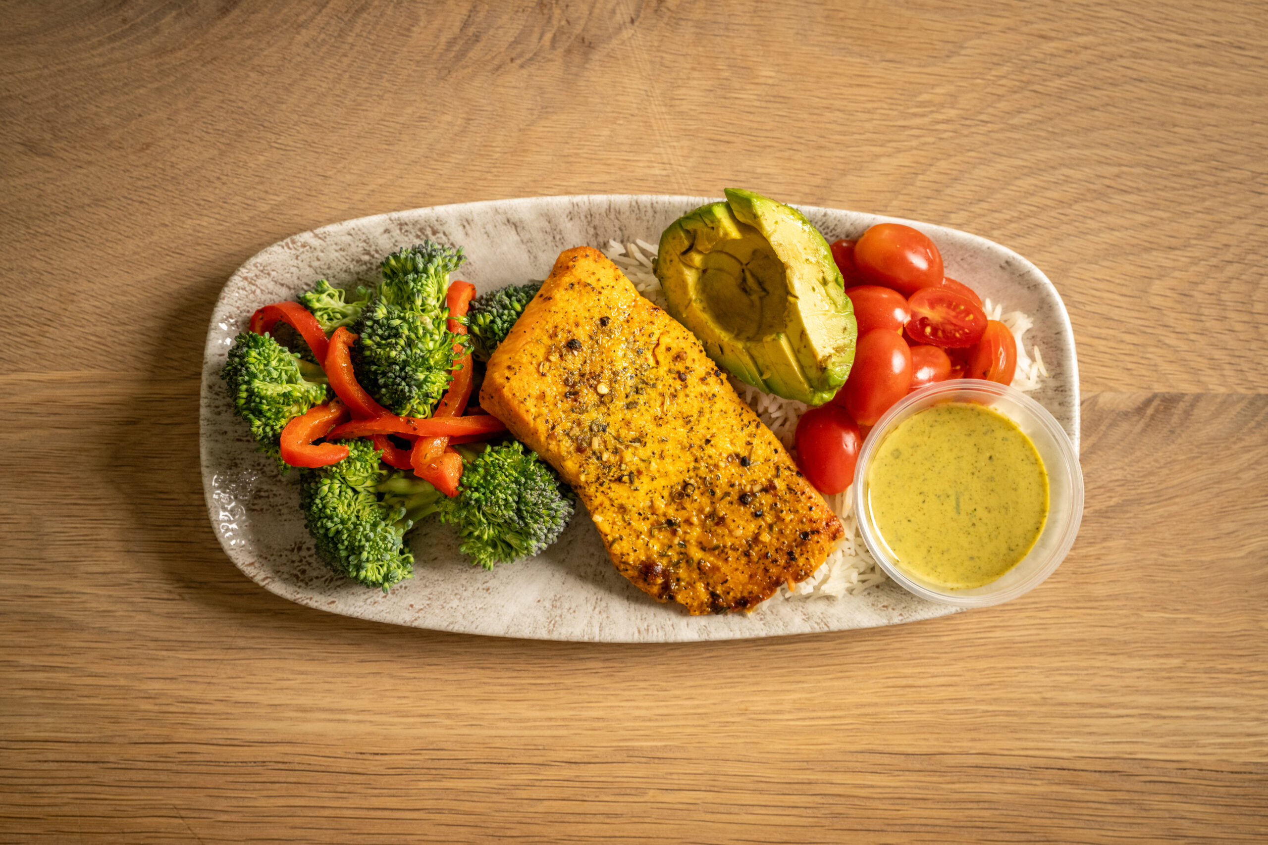 Salmon bowl made with basmati rice, mixed vegetables, and grape tomatoes. Served with home-made green sauce