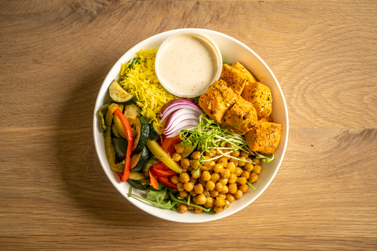 Garlic and herb grilled salmon served with turmeric rice, roasted chickpeas, and mixed roasted veggies with a side of housemade tahini sauce