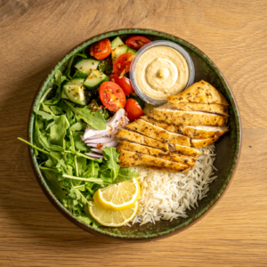 Marinated chicken shawarma, served with basmati rice, arugula, tomatoes, and cucumber salad with a side of hummus