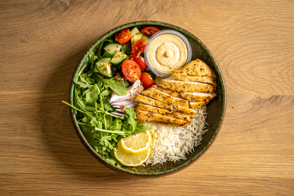 Marinated chicken shawarma, served with basmati rice, arugula, tomatoes, and cucumber salad with a side of hummus