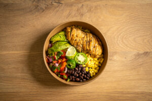 Mexican Chicken Bowl served with turmeric rice, cherry tomatoes, beans, corn, and a side of guacamole